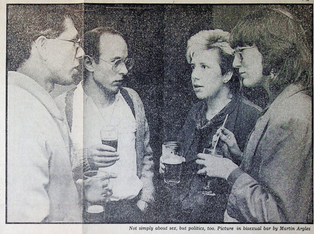 A b/w newspaper photo of four people clutching drinks and talking