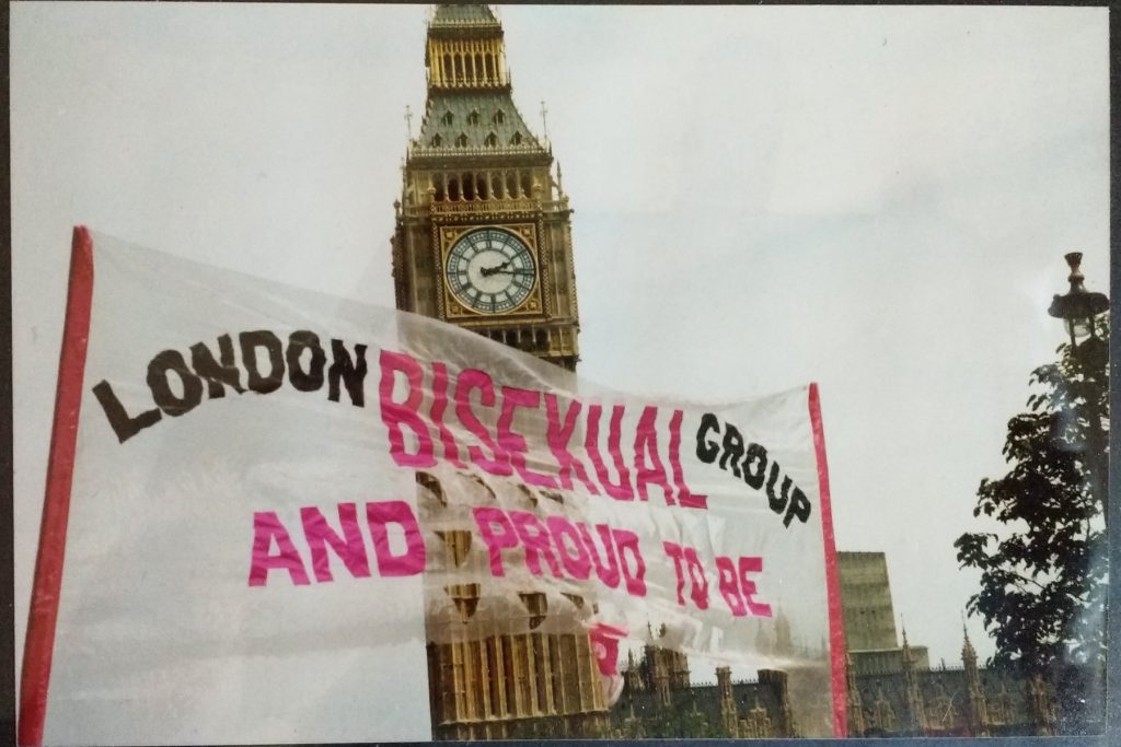 The original banner for the London Bisexual Group after the corners have been cut off, leaving it reading 'London Bisexual Group and proud to be bi' in front of the Elizabeth Tower ('Big Ben') in 1993 or 1994